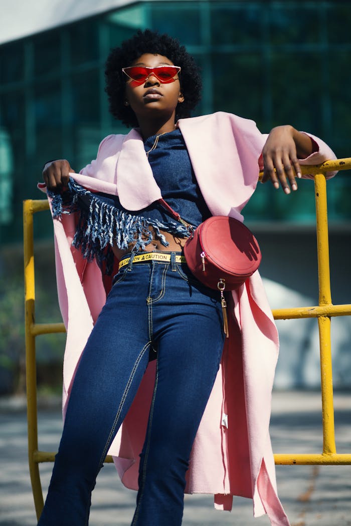 gallery-5 Fashionable portrait of a young woman in denim and pink coat, outdoors in sunlight.