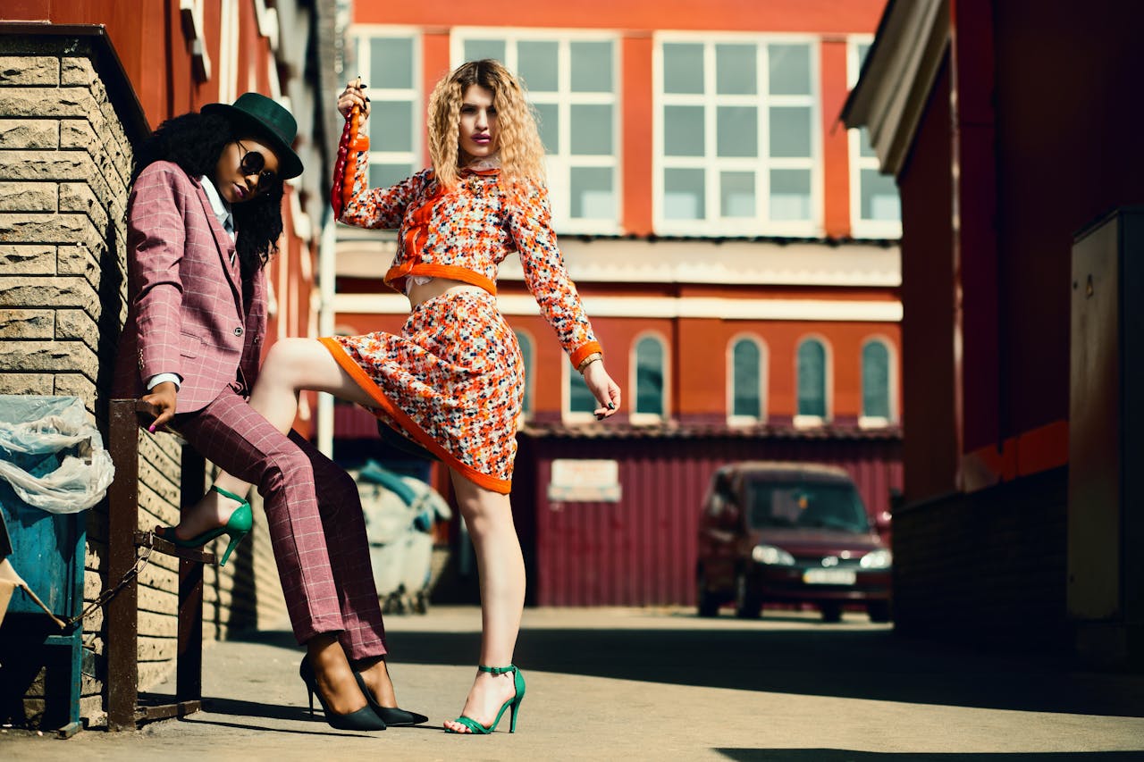 Stylish women posing in an urban alley showcasing contemporary fashion trends.