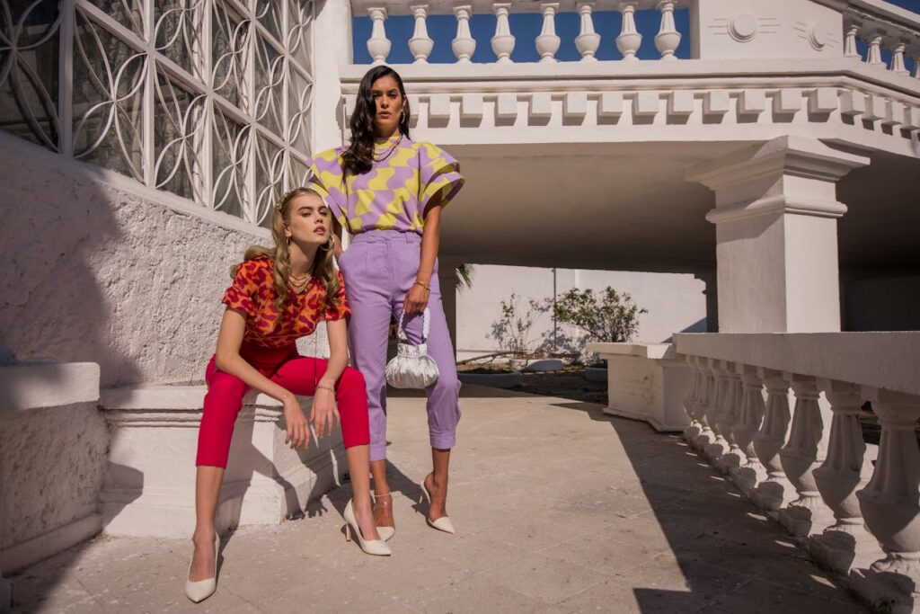 Two fashionable women posing outdoors in vibrant outfits, showcasing modern style.