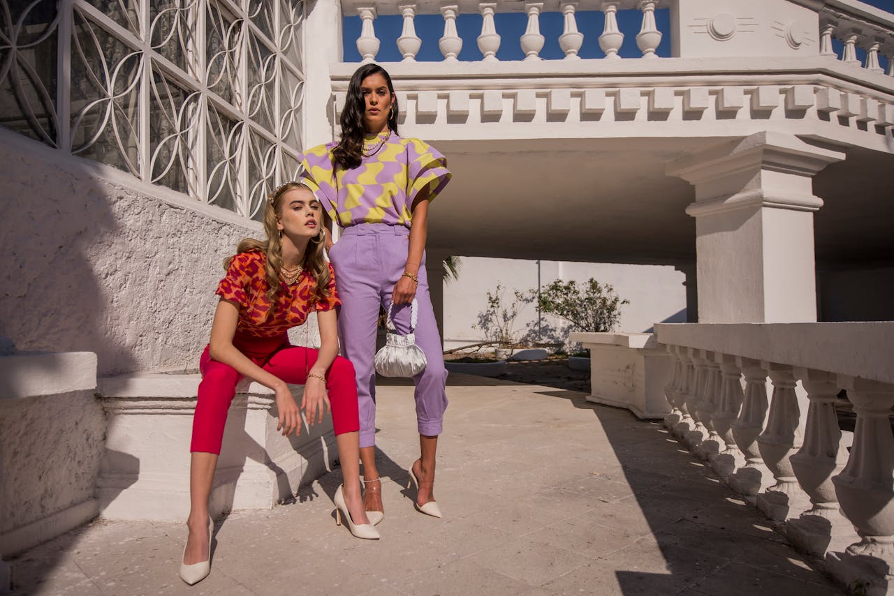 Two fashionable women posing outdoors in vibrant outfits, showcasing modern style.